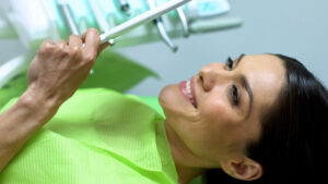 female cosmetic dentistry patient smiling in mirror in dental chair
